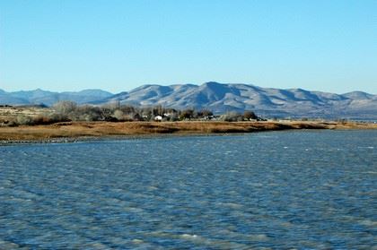 Large Blue Lake With Houses and Mountain Range In Background